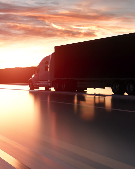An 18-wheeler truck driving into the sunset